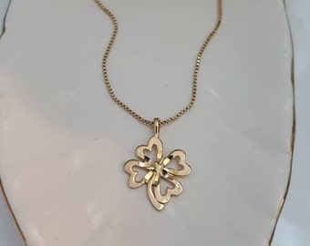 May include: A gold chain necklace with a four-leaf clover pendant. The pendant is made of gold and has a delicate, intricate design.