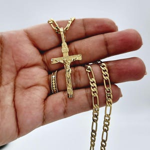 Puede incluir: Un collar de cadena de oro con un colgante de oro de Jes&uacute;s en la cruz.