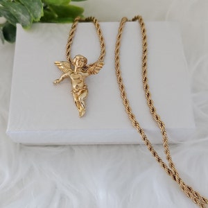 May include: A gold chain necklace with a cherub pendant. The chain is a rope style and the pendant is detailed with wings and a floral design.
