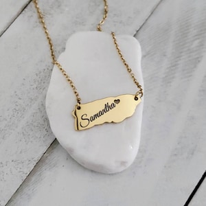 May include: Gold necklace with a pendant shaped like the island of Puerto Rico. The pendant has the name "Samantha" and a small heart engraved on it.