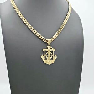 May include: A gold chain necklace with a pendant featuring a detailed anchor with a crucifix on top. The anchor is a symbol of hope and faith.