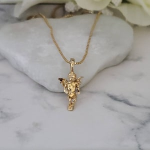 Puede incluir: Un collar de cadena de oro con un peque&ntilde;o colgante de &aacute;ngel. El &aacute;ngel est&aacute; de pie con las alas extendidas y tiene un dise&ntilde;o detallado.