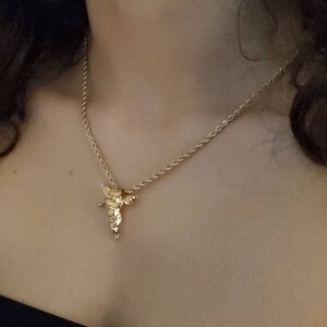 May include: A gold chain necklace with a small angel pendant.