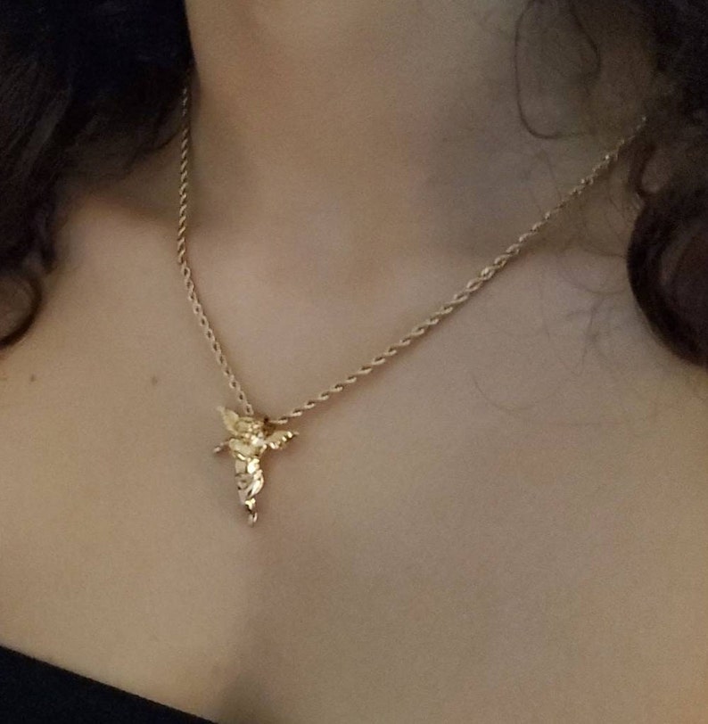 May include: A gold chain necklace with a small angel pendant.