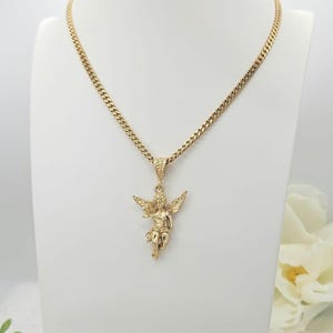 K&ouml;nnte beinhalten: Eine goldfarbene Engels-Anh&auml;nger-Halskette. Der Anh&auml;nger zeigt ein detailliertes Cherub-Design mit ausgebreiteten Fl&uuml;geln. Die Halskette hat eine Panzerkette und wird auf einer wei&szlig;en B&uuml;ste pr&auml;sentiert.