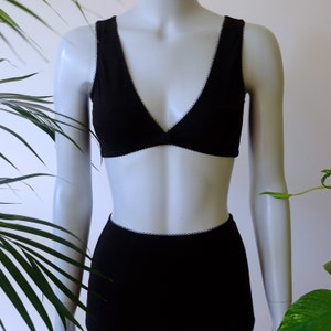 May include: Black lingerie set with a triangle bra and high-waisted underwear. Both pieces have a delicate lace trim.