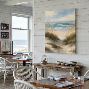 May include: A rectangular canvas wall art print featuring a coastal landscape with tall beach grass in the foreground, a sandy path leading toward the ocean, and a soft blue sky with light clouds above the horizon line of the sea.