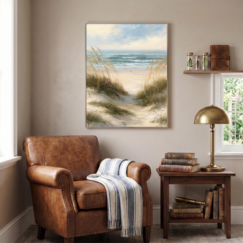 May include: A framed wall art print depicting a coastal beach scene with sand dunes, tall golden beach grass, and a view of the ocean under a soft sky. The painting features muted tones of beige, tan, blue, and white, capturing a serene landscape.