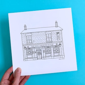May include: Black and white line drawing of The Hallamshire House pub. The illustration shows the building's facade, including windows, doors, and signage. The artwork is on a white paper, held against a bright blue background.