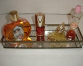 Mirrored Glass Tray. Four Perfumes. Vintage Jergens Pink Frosting. Vintage Avon Flower Bottle. Gloria Vanderbilt. Watkins Scarlet