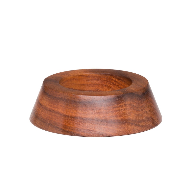 K&ouml;nnte beinhalten: Eine handgefertigte Holzschale mit breitem, konischem Boden und kreisf&ouml;rmiger &Ouml;ffnung. Die Schale besteht aus dunklem, rotbraunem Holz, das die nat&uuml;rliche Maserung zeigt. Das Design ist schlicht und elegant, geeignet f&uuml;r dekorative oder funktionale Zwecke. Durchmesser ca. 15 cm.