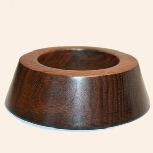 May include: A dark brown wooden ring with a wide, rounded base and a smaller, circular opening in the center.