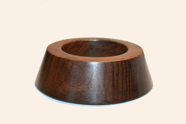 May include: A dark brown wooden ring with a wide, rounded base and a smaller, circular opening in the center.