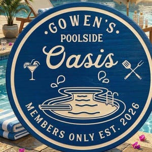 May include: A round blue wooden sign with white text and graphics. The text reads GOWEN'S POOLSIDE OASIS and MEMBERS ONLY EST. 2026. Graphics include a swimming pool, a cocktail glass, and crossed grilling utensils, all in white.