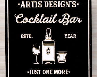 May include: Black wooden sign with white text that reads "Artis Design's Cocktail Bar Estd. YEAR Just One More." The sign features a stylized illustration of a bottle, a wine glass, and a shot glass.