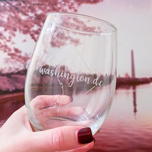 May include: A clear glass wine glass with an etched design of the Washington, D.C. skyline and the text "washington.dc."