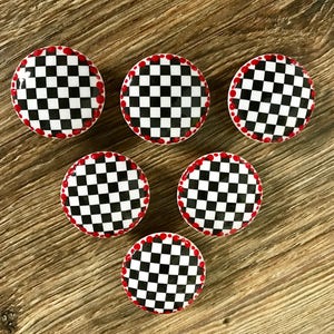 May include: Six black and white checkered round cabinet knobs with a red dot border.
