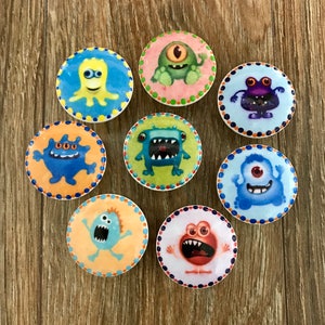 May include: Eight colorful ceramic knobs with different monster designs. Each knob features a unique monster with different colors, patterns, and expressions. The knobs are perfect for adding a whimsical touch to any room.