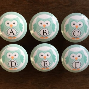 May include: Six light blue owl-shaped cabinet knobs with white and gray chevron patterns. Each knob features a white circle with a black letter, A through F.