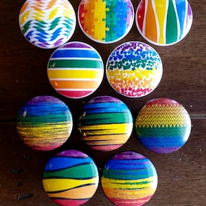 May include: Ten round rainbow pride buttons with different patterns, including stripes, puzzle pieces, and zigzags.