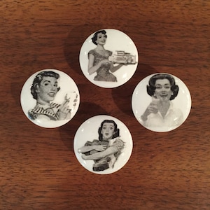 May include: Set of four white ceramic knobs with black and white images of women from vintage advertisements. The women are depicted in various poses, including holding a tray of food, a glass of water, and a book.
