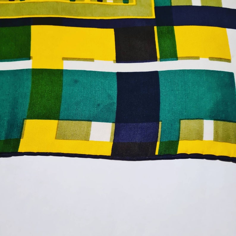 May include: A colorful geometric pattern fabric with yellow, green, blue, and white squares. The fabric has a dark blue border.