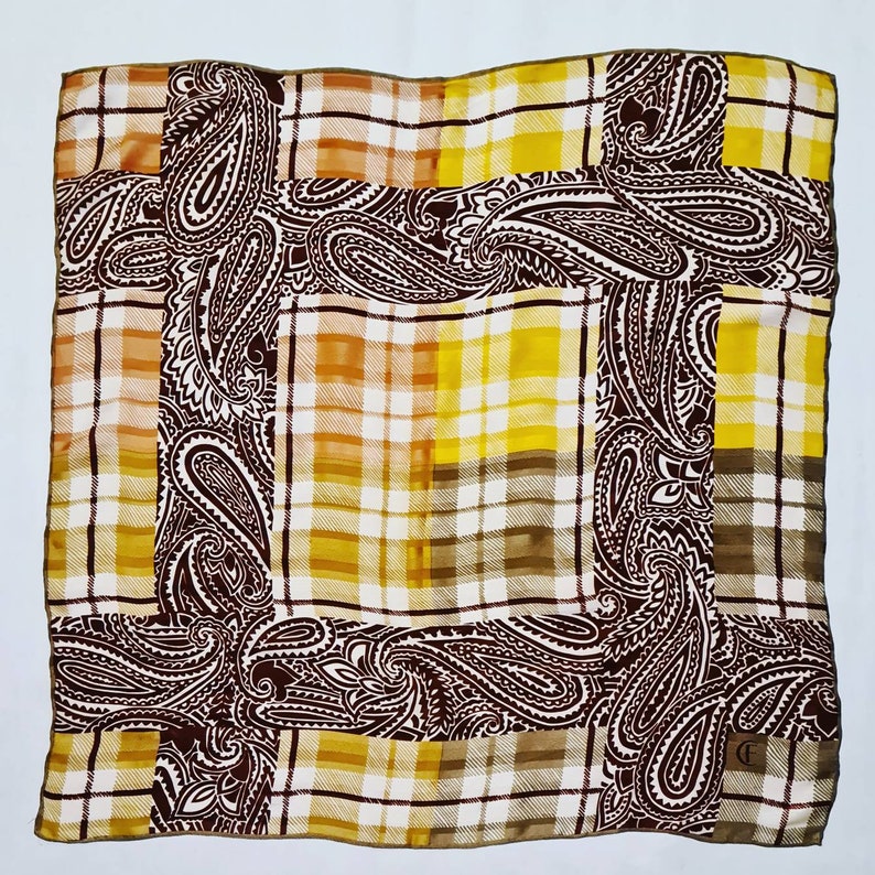 Peut inclure: Un foulard en soie brun et jaune avec un motif paisley et un design &agrave; carreaux. Le foulard est bord&eacute; d'une bordure dor&eacute;e.