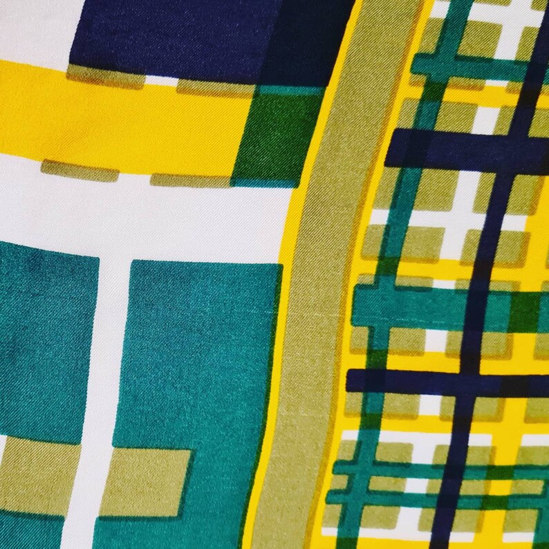 May include: Abstract geometric pattern fabric in yellow, green, white, and navy blue. The fabric has a checkered pattern with a large square in the center.