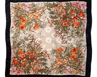 May include: Square silk scarf with a floral design. The scarf features a cream-colored center with orange, pink, and green floral patterns. A black border frames the scarf. The scarf has a label in the bottom right corner.