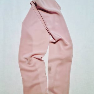 Puede incluir: Una larga bufanda rosa pálido hecha de una tela suave y fluida.