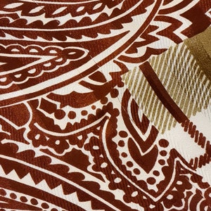Peut inclure: Gros plan sur un tissu &agrave; motif paisley brun et blanc avec un motif ray&eacute; or et blanc dans le coin sup&eacute;rieur droit.
