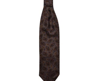 May include: A brown ascot tie with a paisley pattern in shades of brown and gold. The tie is made of a smooth fabric and is designed to be worn around the neck. The tie is a classic accessory for formal occasions.
