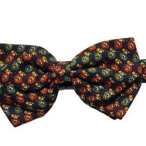 May include: A navy blue bow tie with a repeating pattern of red, yellow, and green floral shapes.