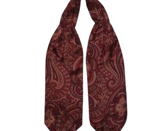 May include: A burgundy paisley ascot scarf. The scarf features a repeating pattern of curved, teardrop-shaped motifs in shades of burgundy, brown, and tan. The scarf is made of a soft, flowing material.
