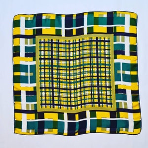 May include: A square silk scarf with a geometric pattern in shades of yellow, green, and black. The pattern is a series of overlapping squares and rectangles.