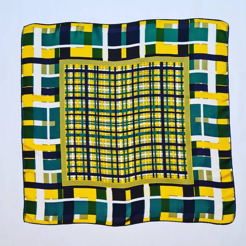 May include: A square silk scarf with a geometric pattern in shades of yellow, green, and black. The pattern is a series of overlapping squares and rectangles.
