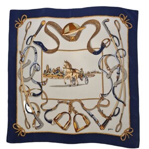 May include: A white silk scarf with a blue border featuring a horse-drawn carriage and equestrian equipment, including a riding crop, bridles, and stirrups.