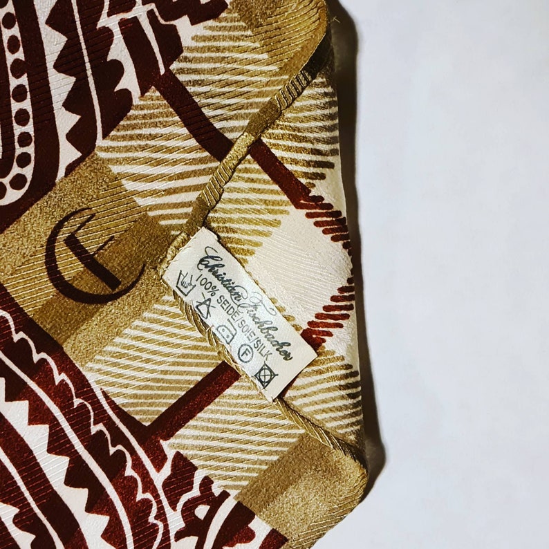 Peut inclure: Un foulard en soie &agrave; motifs marrons et blancs avec une &eacute;tiquette indiquant "Christian Lacroix 100% Seide/Soie/Silk".