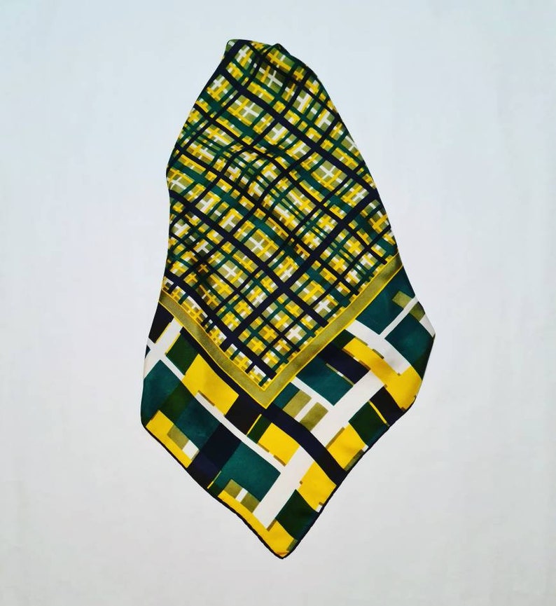 May include: A green, yellow, and black patterned silk scarf with a geometric design.