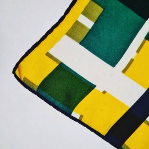 May include: A close-up of a yellow, green, and black patterned fabric with a black border. The fabric has a geometric design with squares and rectangles.