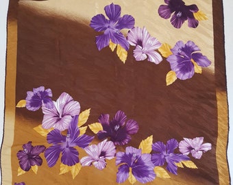 May include: A brown silk scarf with a gold border and a purple floral pattern. The flowers are hibiscus and are arranged in a diagonal pattern.