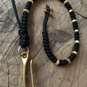May include: A black paracord keychain with a brass hook and hexagonal brass beads.