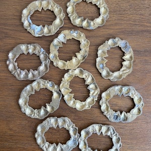 K&ouml;nnte beinhalten: Zehn goldfarbene, dekorative Ringe aus Metall mit filigranen Designs. Die Ringe sind kreisf&ouml;rmig mit einem Loch in der Mitte.