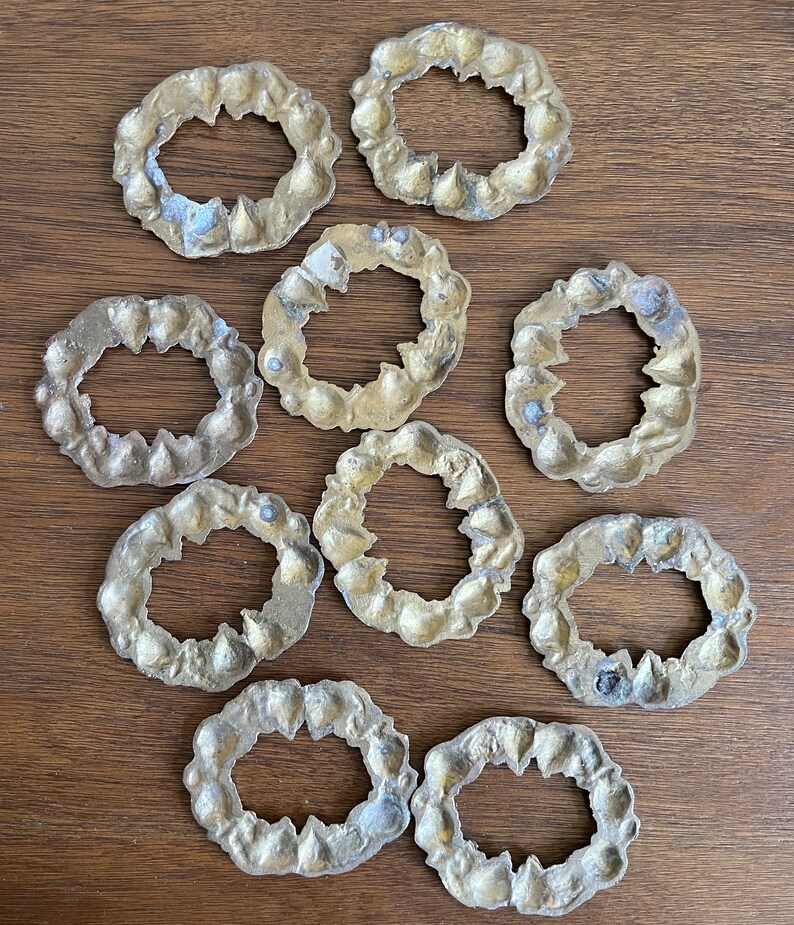 K&ouml;nnte beinhalten: Zehn goldfarbene, dekorative Ringe aus Metall mit filigranen Designs. Die Ringe sind kreisf&ouml;rmig mit einem Loch in der Mitte.