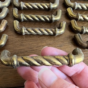 May include: A collection of antique brass cabinet knobs with a rope design. The knobs are in various sizes and are all in good condition.
