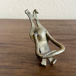 May include: A brass door pull with an ornate design. The pull has a ring handle and a keyhole.