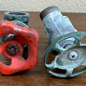 May include: Two vintage water valve handles. One is red with a four-pointed star design. The other is green with a five-pointed star design.