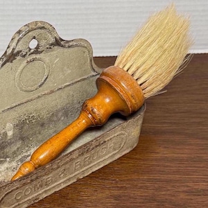 May include: A vintage wooden shaving brush with natural bristles, in a metal holder with the words "Come & Brush" on the front.
