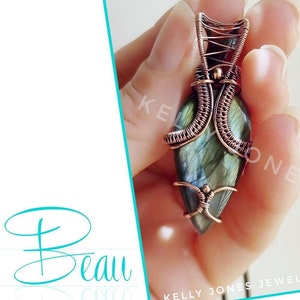 以下が含まれることがあります： 緑のラブラドライトの宝石を特徴とする、銅線で巻かれたペンダント。ペンダントは手に持たれています。画像の下には「Pendant Tutorial by Kelly Jones」というテキストがあります。「Now on Etsy」というテキストは、そのテキストの下にあります。