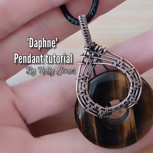 Könnte beinhalten: Ein mit Kupferdraht umwickelter Anhänger mit einem Tigerauge-Stein. Der Anhänger hat die Form einer Träne und ist an einer schwarzen Schnur befestigt. Der Anhänger ist mit 'Daphne' Anhänger-Tutorial von Kelly Jones beschriftet.